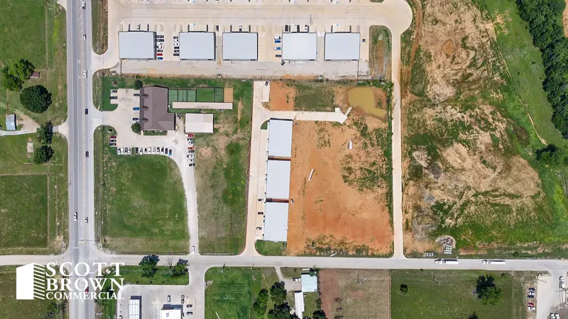 Overhead aerial of the Fusion Business Park site showing a completed row of buildings, graded pads awaiting further construction, internal roads and marked parking.